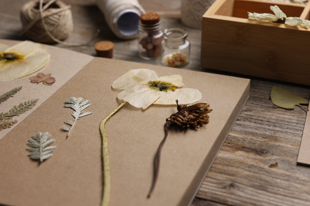 Dry flowers, leaves and notebook on wooden table, closeup