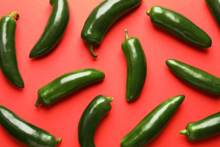 Green jalapeno peppers on red background, flat lay