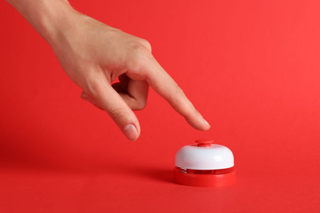 Woman pressing button on red background, closeup
