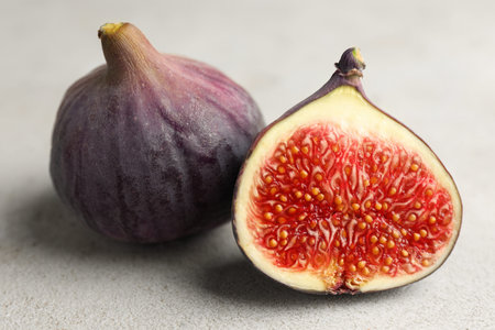 Whole and cut figs on textured table, closeup