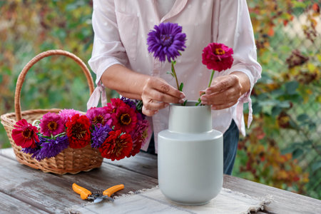 Senior woman making beautiful bouquet of flowers at wooden table in garden, closeupのeditorial素材