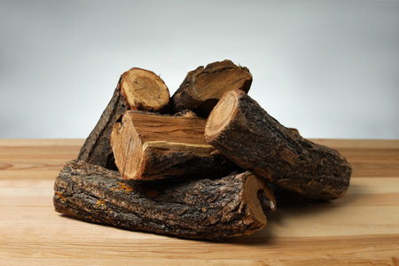 Pile of cut firewood on wooden table against gray background, closeup