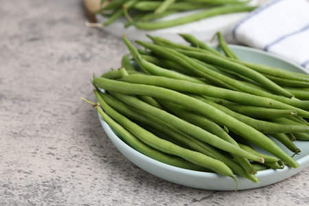 Fresh green bean pods on gray textured table, closeup