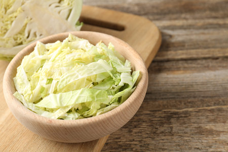 Cut Savoy cabbage on wooden table, closeup. Space for text