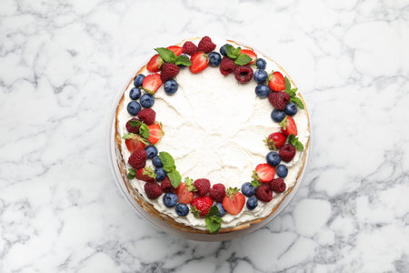 Delicious crepe cake with fresh berries on white marble table, top view