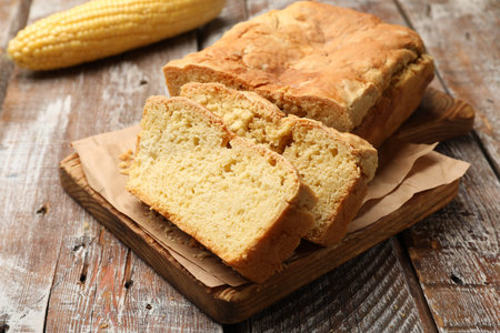 Freshly baked cut cornbread on wooden table, closeup