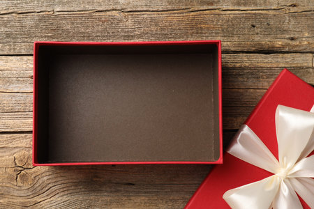 Opened gift box with beautiful lid on wooden table, top view