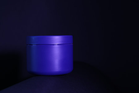 Jar of hair care cosmetic product on dark background. Space for text