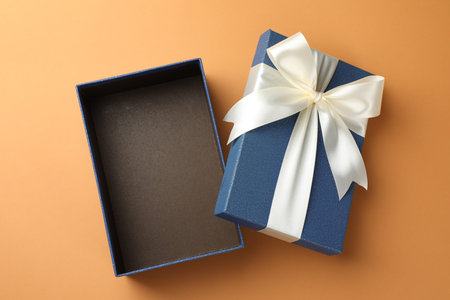Open gift box with beautiful lid on orange background, top view