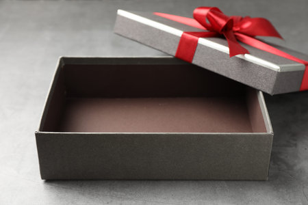 Opened gift box with beautiful lid on gray table, closeup