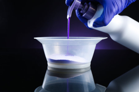 Woman making hair care product for blonde hair at black mirror table against dark purple background,...