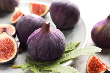Fresh ripe figs and green leaf on table, closeup