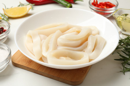 Uncooked squid rings and spices on white table, closeupの写真素材
