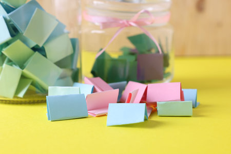 Colorful paper notes and glass jars on yellow table, closeupの写真素材