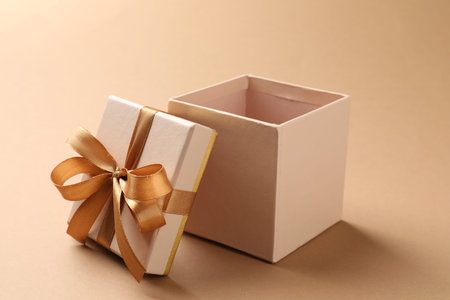Opened gift box with beautiful lid on beige background, closeup