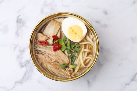 Tasty ramen with enoki and king oyster (eryngii) mushrooms on white marble table, top view