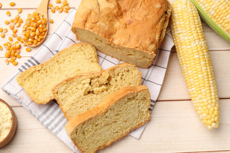 Freshly baked cornbread, cobs and seeds on wooden table, flat lay