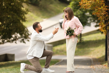 Man with engagement ring making marriage proposal to his girlfriend outdoorsの写真素材