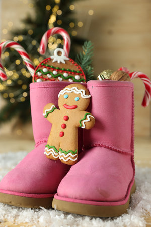 Saint Nicholas day tradition. Boots with sweets and artificial snow on floor indoors, closeup
