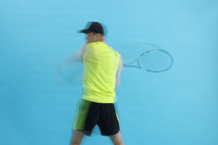 Man with racket playing tennis on light blue background, motion blur effectの写真素材