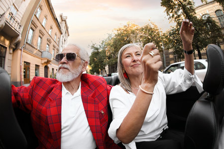 Senior couple enjoying cabriolet ride in city, wide angle lensの写真素材