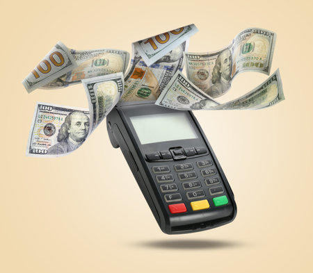 Payment terminal and dollars in air on beige background