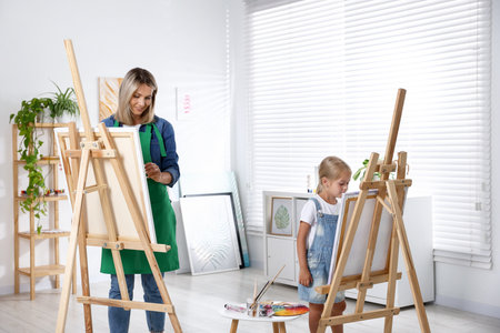 Choice of profession. Mother teaching her daughter to paint in studioの写真素材