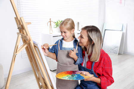 Choice of profession. Mother teaching her daughter to paint in studioの写真素材