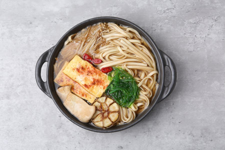 Tasty ramen with enoki and king oyster (eryngii) mushrooms on light gray table, top view