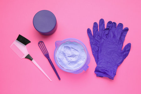 Care cosmetic product for blonde hair in bowl and hairdresser's tools on pink background, flat layの写真素材