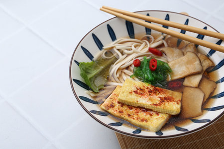 Tasty ramen with king oyster (eryngii) mushrooms in bowl on white tiled table, closeupの写真素材