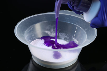 Woman making hair care product for blonde hair at black mirror table, closeup