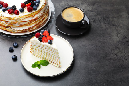Piece of tasty crepe cake with berries served on gray table