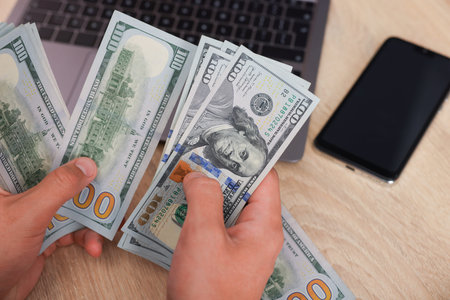 Man counting dollar banknotes at wooden table, closeupの写真素材