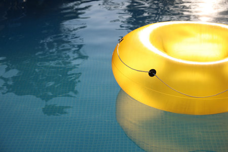 Yellow inflatable ring in swimming pool outdoors, closeup. Space for text