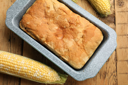 Freshly baked cornbread and cobs on wooden table, flat lay