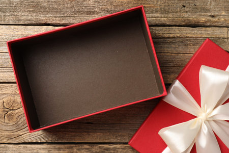 Opened gift box with beautiful lid on wooden table, top view