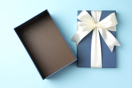Opened gift box with beautiful lid on light blue background, top view
