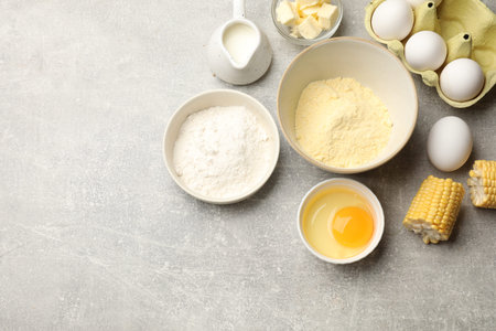Cornbread preparation. Different ingredients on light gray table, flat lay. Space for text