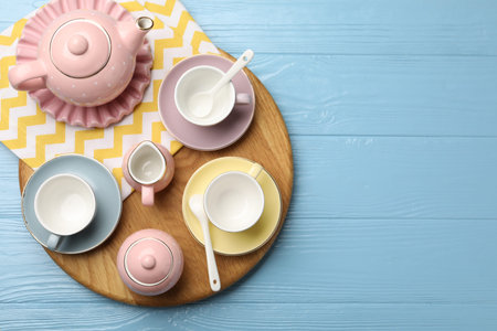 Beautiful ceramic tea set for children and napkin on light blue wooden table, top view. Space for textの写真素材