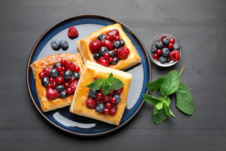 Tasty puff pastries with berries and mint on gray wooden table, flat layの写真素材