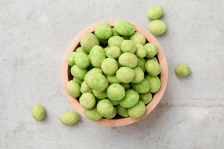 Wasabi coated peanuts in bowl on light table, top viewの写真素材