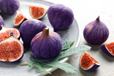 Fresh ripe figs and green leaf on gray table, closeupの写真素材