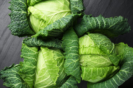 Fresh Savoy cabbages on black textured table, flat layの写真素材