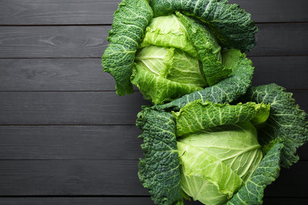 Fresh Savoy cabbages on black wooden table, flat lay. Space for textの写真素材