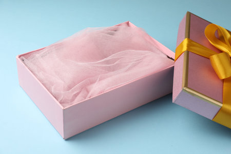 Opened gift box with beautiful lid on light blue background, closeup