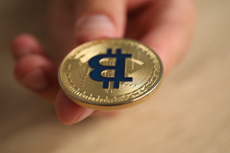 Cryptocurrency. Man with golden bitcoin at table, closeupのeditorial素材