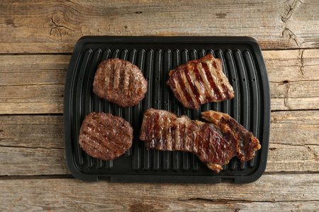 Grilled beef meat on wooden table, top view