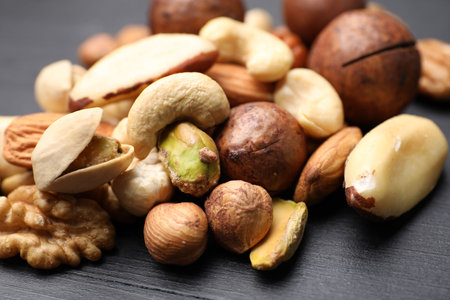 Mix of different nuts on black wooden table, closeup