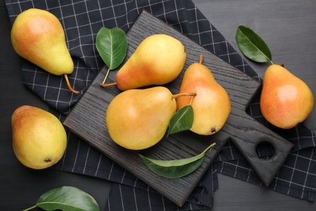 Many fresh pears and leaves on black table, flat lay